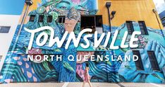 a woman standing in front of a building with the words townsville written on it