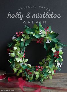 a christmas wreath with holly and mistletoe on it sitting next to a chalkboard