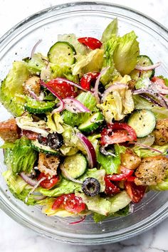 a salad in a glass bowl on a marble table