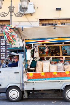 a food truck parked in front of a building with lots of bags on the back