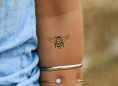 a woman's arm with a bee tattoo on the left side of her arm