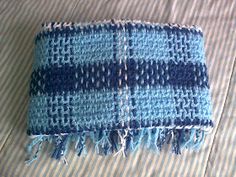 a blue and white blanket laying on top of a bed next to a striped pillow