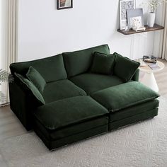 a large green couch sitting on top of a white rug in a living room next to a window