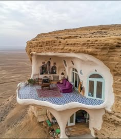 a house built into the side of a cliff with a couch and table in it