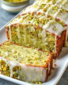 a loaf of lemon pistachio bread on a white platter with two slices cut off