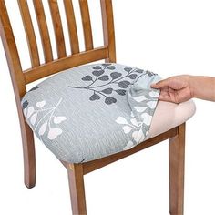 a person holding onto a cushion on top of a wooden chair