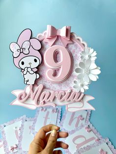 someone is holding up a pink and white cake topper with the number nine on it