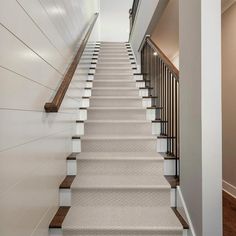 the stairs are lined with white carpet and wood handrails