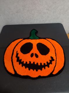 a halloween pumpkin shaped rug sitting on top of a black table next to a wall