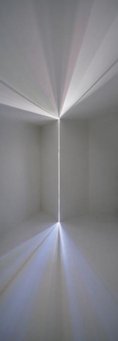 an empty room with white walls and light coming from the ceiling in front of it