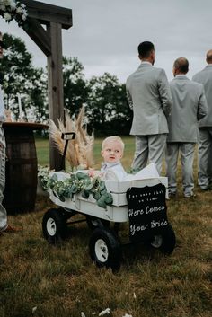 a baby sitting in a wagon at a wedding