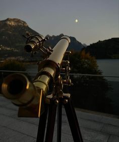 a telescope sitting on top of a wooden tripod next to a body of water