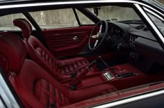 the interior of a classic car with red leather seats and steering wheel, along with other accessories