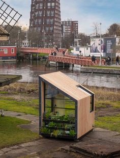 a small wooden structure with plants growing in it on the side of a body of water