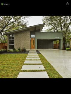 a house with grass and trees in the front yard, along with a walkway leading up to it