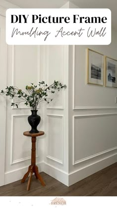 a vase with flowers sitting on top of a wooden table next to a white wall