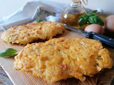 two cheesy patties on a cutting board next to an egg and knife