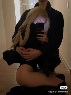 a man is taking a selfie with a blonde haired woman sitting on the floor