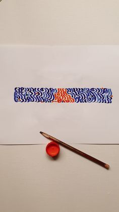 a piece of paper with an orange and blue design on it next to a paintbrush