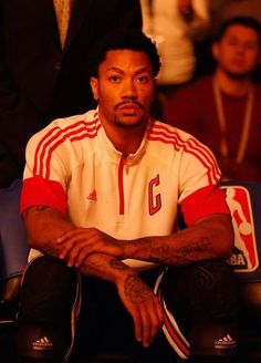 a man sitting in the stands at a basketball game with his hands on his knees