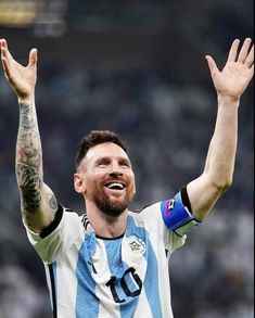 a man with his hands up in the air while wearing a striped shirt and tattoos