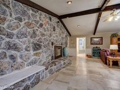 a living room with stone walls and ceiling fan