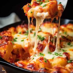 a spatula is lifting some pizza from a skillet with cheese and tomato sauce