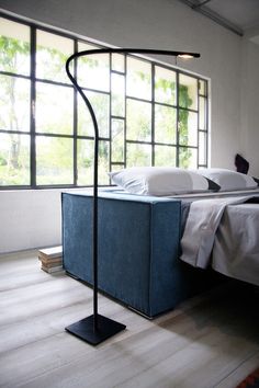 a bed sitting under a window next to a blue box with pillows on top of it