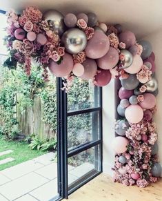 balloons and flowers are hanging on the wall in front of a window with an open door