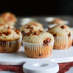 several muffins sitting on a white plate next to a red napkin and spoon