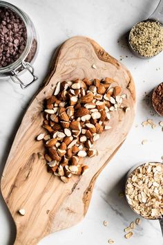 nuts and seeds on a cutting board next to measuring spoons