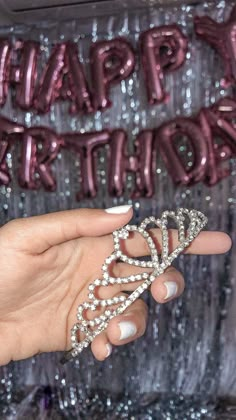 a hand holding a diamond ring in front of a happy birthday balloon wall with the words happy birthday on it