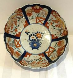 an orange and blue plate with flowers on it sitting on a white tableclothed surface