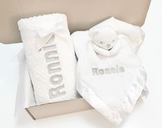 a baby gift set with a teddy bear and bib in a white box on a table