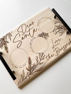 a wooden cutting board with the words dear santa written in cursive writing on it