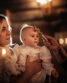 a woman holding a baby in her arms while she is combing it's hair