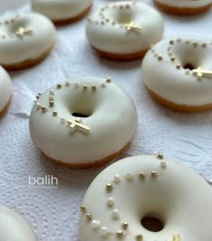 white frosted donuts with gold sprinkles are arranged on a table