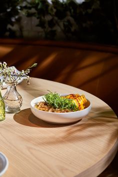 a table with two bowls of food on it and a bottle of wine in the background