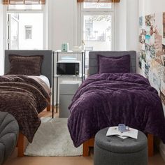 two beds in a room with purple comforters and pillows on the bed, next to each other