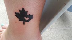 a black maple leaf with a heart tattoo on the ankle and foot is seen from above