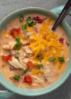 a bowl of soup with chicken, cheese and tomatoes