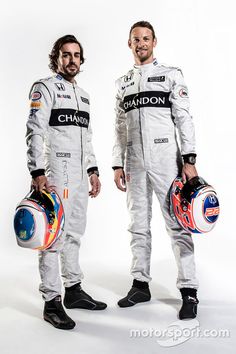 two men standing next to each other holding helmets