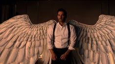 a man standing in front of an angel wings statue with his hands on his hips