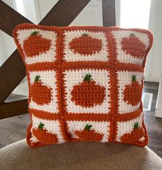 an orange and white crocheted pillow sitting on top of a chair