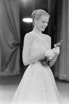 an old photo of a woman in a dress holding her oscar award for best actress