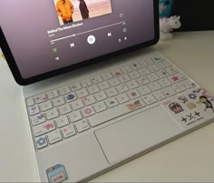 an open laptop computer sitting on top of a white table next to a stuffed animal