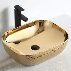 a gold bathroom sink sitting on top of a white counter