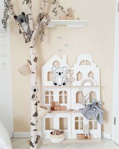 there is a white tree in front of the doll house on the shelf next to it