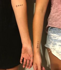 two people holding hands with small tattoos on their arms and the words love are written in cursive writing