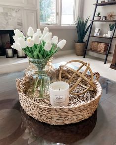 a glass vase with white tulips in it on a coffee table